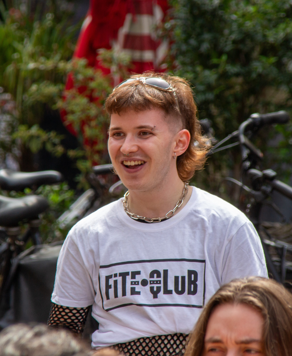 a person wears the fiteqlub t-shirt at the festival and smiles while volunteers