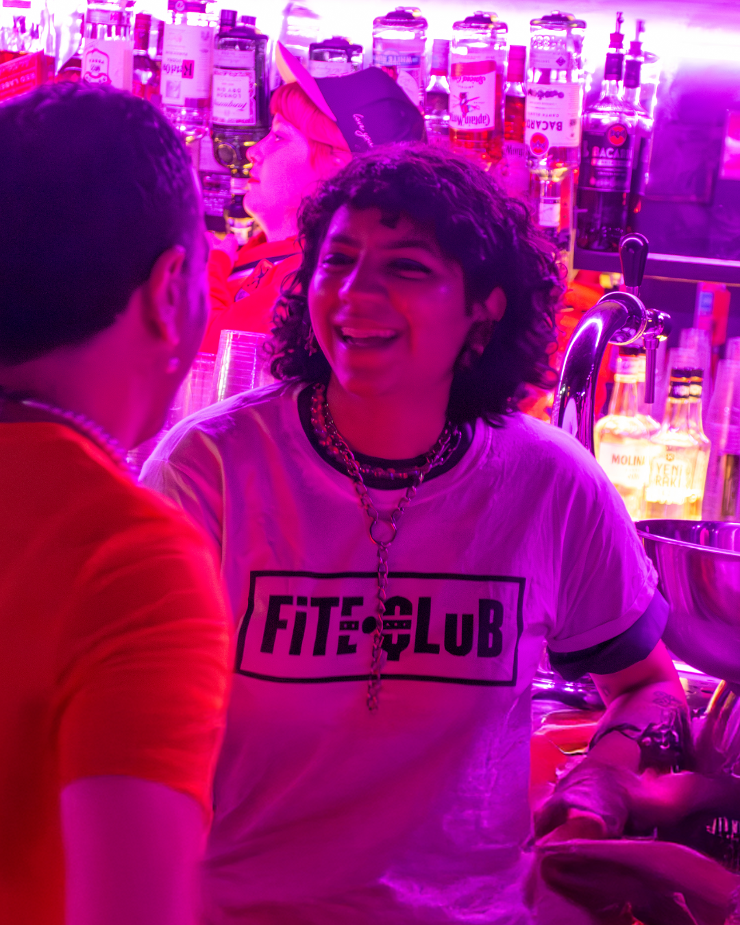 person smiling in the club with a t-shirt that says: Fite Qlub