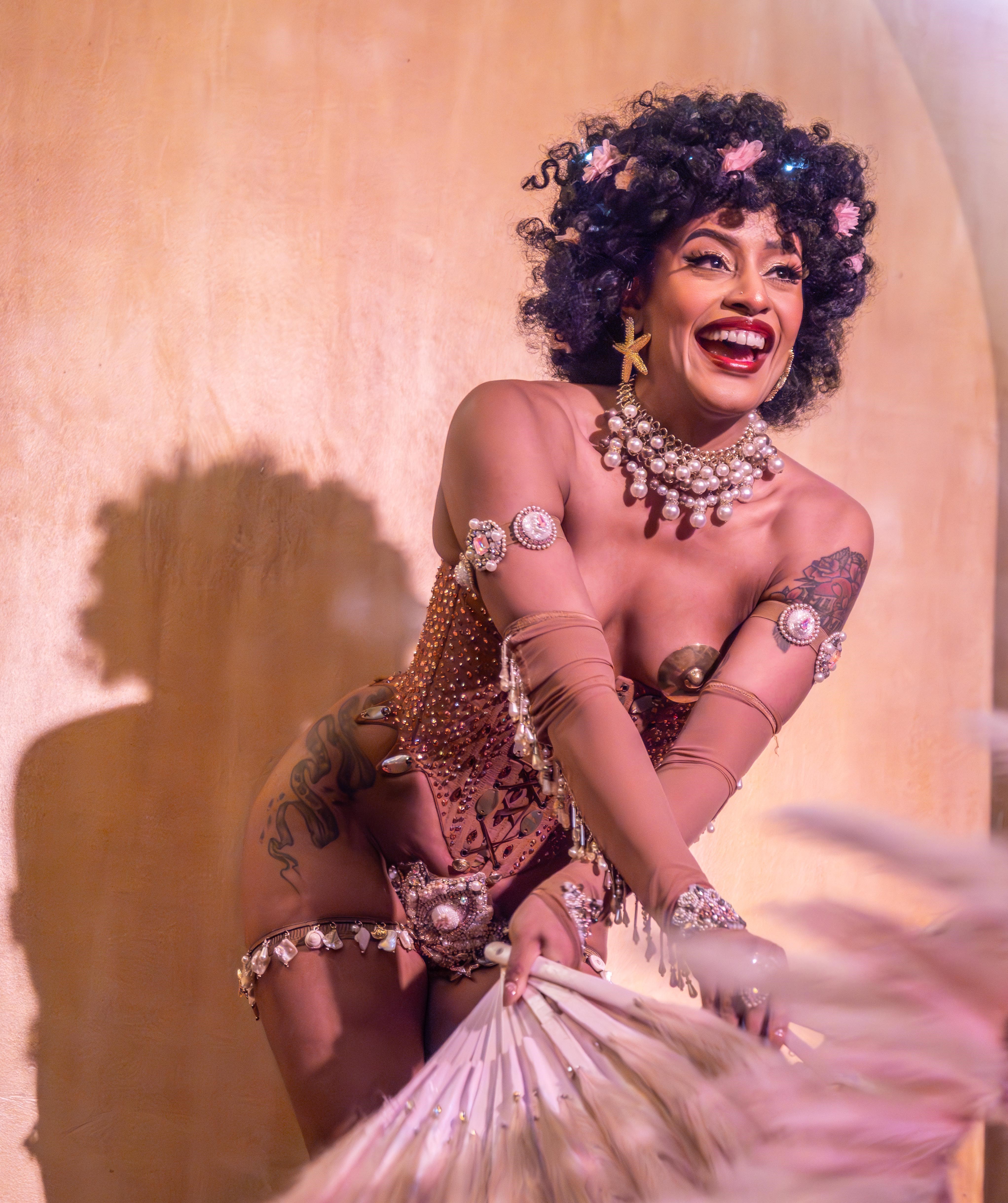 Venuss performing burlesque smiling holding big feathers