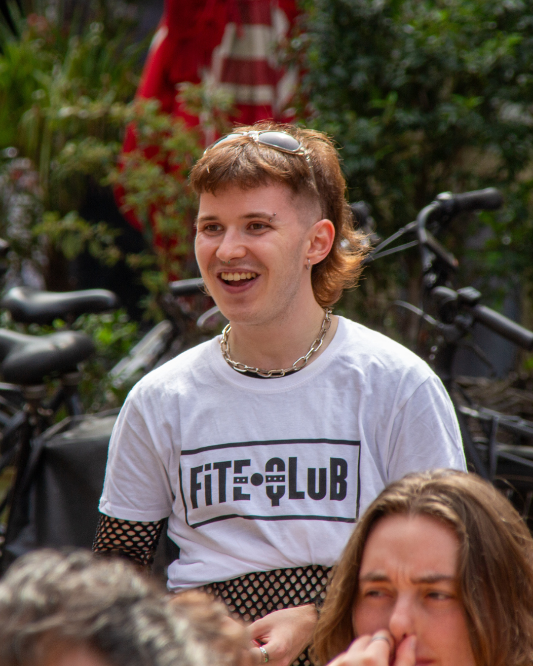 person smiling in a crowd with a t-shirt that says: Fite Qlub